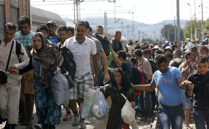 Migrants rush to board a train that would take them towards Serbia, at the railway station in the southern Macedonian town of Gevgelija, Wednesday, Aug. 19, 2015. Record numbers of migrants from countries like Syria, Iraq and Afghanistan uses the so-called Balkan route that passes trough Macedonia. (AP Photo/Darko Vojinovic)