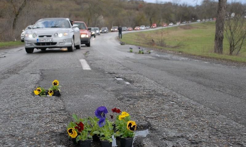 Drumurile noastre toate, se vor asfalta… odată: Până atunci localnicii pavează gropile cu flori